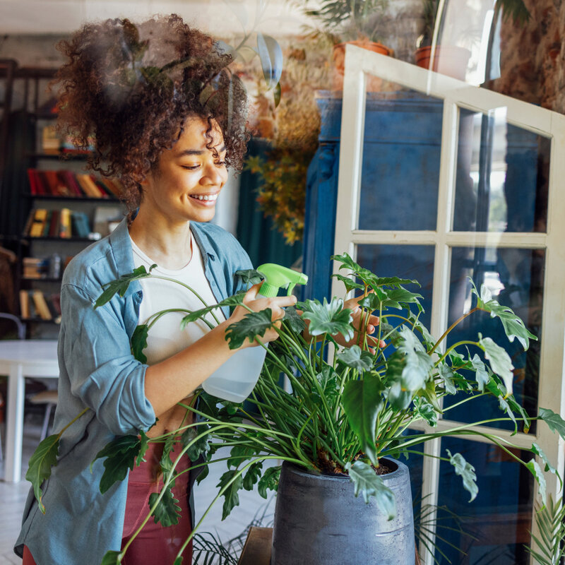Happy and healthy woman taking care of her plants and breathing clean air